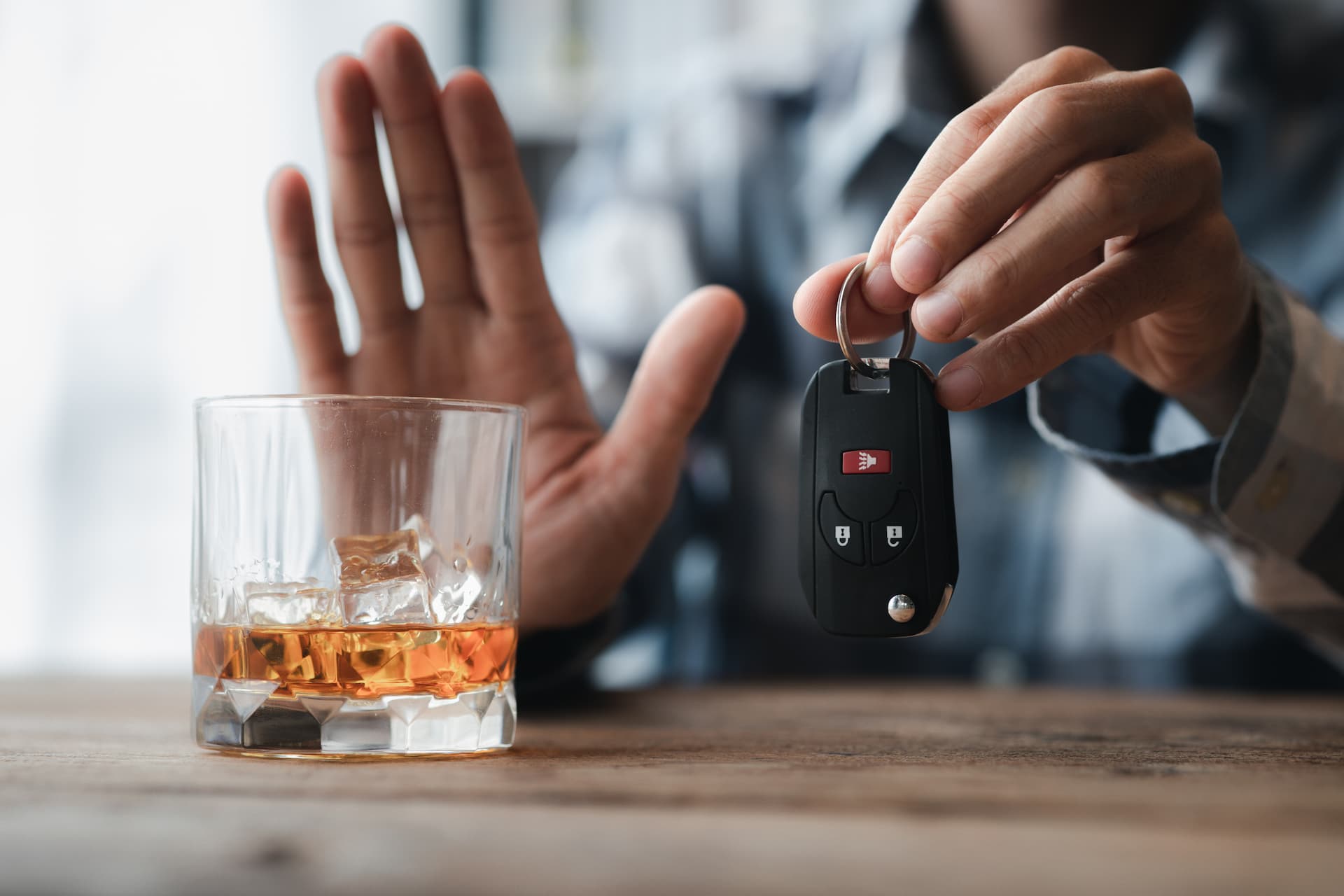 man holding keys next to glass of alcohol gesturing not to drink and drive
